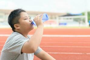 Fat asian boy drink water from a plastic bottle photo