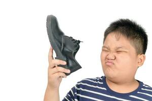 Disgusted boy holding a pair of smelly leather shoes photo