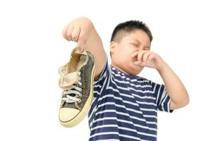 Disgusted fat boy holding a pair of smelly shoes photo