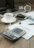 calculator on work table with computer notebook mobile phone and hot coffee photo