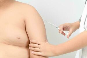 médico preparar inyectando vacunación en brazo de obeso grasa niño foto