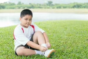 Obese fat asian boy lacing sport shoe. photo