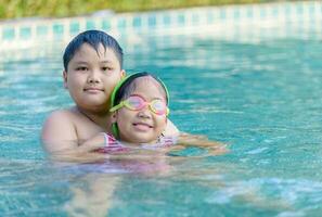 contento hermano y hermana jugando en nadando piscina, foto