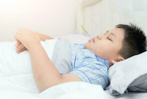 sick boy with thermometer sleep on bed photo