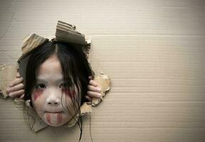 Ghost kid looking through hole on cardboard. photo