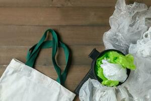 plastic bags in bin and canvas tote bag on wood photo