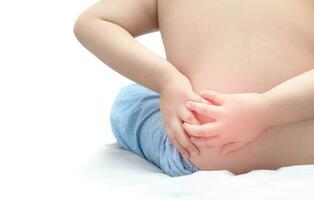 boy holding his back in pain and suffers from backache photo