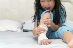 foot pain. Little kid with broken leg on bed, photo