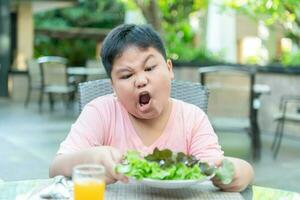 Boy with expression of disgust against vegetables photo