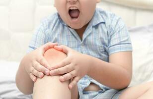 Obese fat boy suffering from knee pain and sit on bed photo