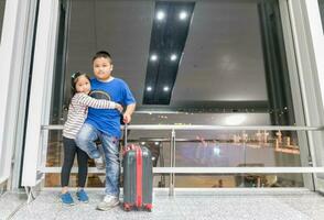 hermano y hermana en pie con equipaje preparar a viaje en aeropuerto foto