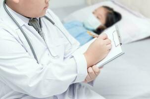 little doctor writing on clipboard and sick girl on bed photo