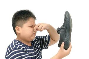 Disgusted boy holding a pair of smelly leather shoes photo