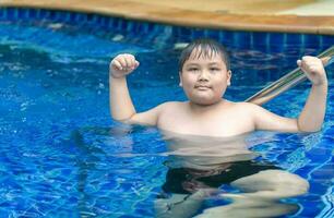 Obese fat boy show muscle in swimming pool photo