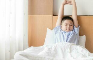 obese fat boy wakes up and stretching on bed. photo