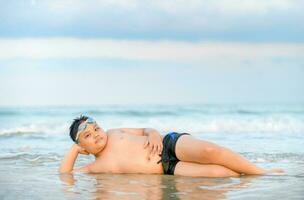 cute asian obese boy playing wave on beach, photo