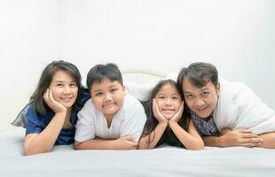 asiático contento joven familia acostado en cama juntos foto
