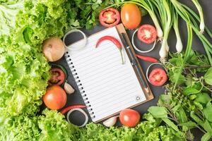 mix vegetables with blank notebook on black bcakground photo