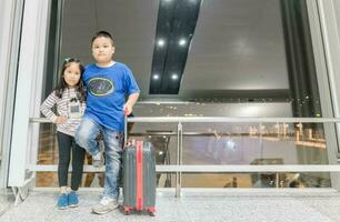 brother and sister standing with baggage photo