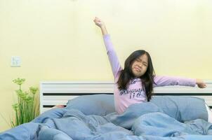 Cute girl stretching in bed after waking up, photo