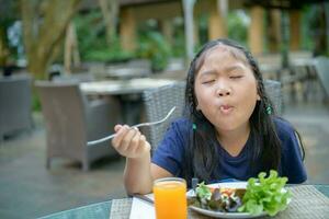 asiático linda niña disfrutar a comer vegetal ensalada foto