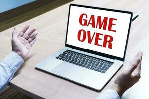 Businessman spread out your hands with message GAME OVER on display laptop photo
