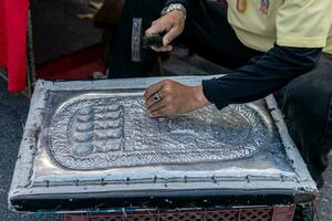 Man hand carving metal engraving on streets of Chiang Mai photo