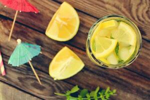 Drink with lemon, mint, ice, water on wooden background. Toned image photo