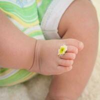 Legs baby with chamomile on the fingers photo
