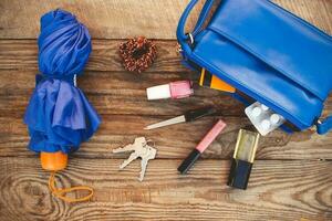 Blue purse, umbrella and women's accessories. Things from open lady handbag. Top view. Toned image. photo