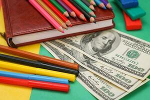 Pens, colored pencils, plasticine, book, hundred dollar bills photo