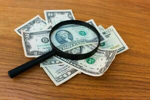 Magnifying glass and dollars on the table photo