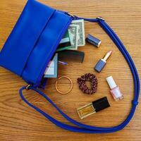 Things from open lady handbag. women's purse on wood background. Cosmetics and women's accessories fell out of the blue handbag. photo