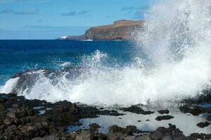 grande olas estrellarse en contra el rocas en el Oceano foto