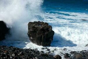 grande olas estrellarse en contra el rocas en el Oceano foto