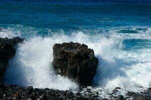 grande olas estrellarse en contra el rocas en el Oceano foto