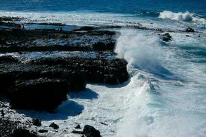 grande olas estrellarse en contra el rocas en el Oceano foto