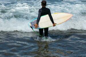 surfistas consiguiendo Listo a entrar el agua y caminando con el tablero a lo largo el costa. foto