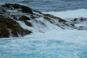 grande olas estrellarse en contra el rocas en el Oceano foto