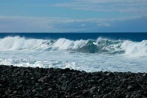 grande olas estrellarse en contra el rocas en el Oceano foto