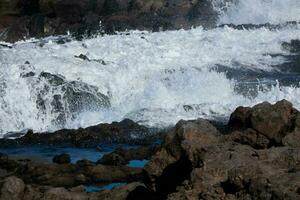 grande olas estrellarse en contra el rocas en el Oceano foto