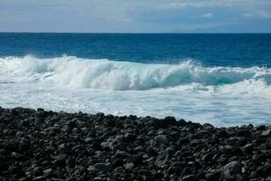 grande olas estrellarse en contra el rocas en el Oceano foto