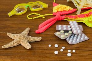 Summer beach accessories and medicine on the table. The concept of medication required in the journey photo