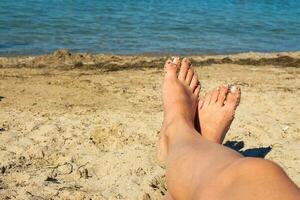 hembra pies en el azul mar antecedentes. un mujer toma el sol en el playa. niña tomado imágenes de su pies ser. foto