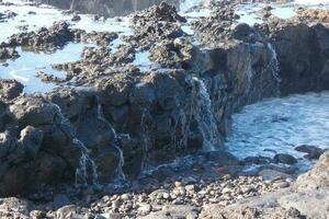 grande olas estrellarse en contra el rocas en el Oceano foto