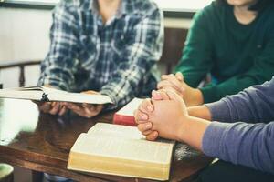 Small group of asian people praying worship believe. Teams of friends worship together before studying Holy bible. family praying together in church. Small group learning with prayer concept. photo