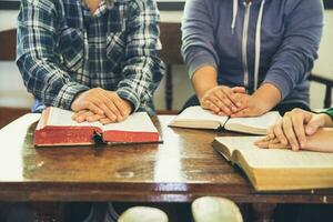 Small group of asian people praying worship believe. Teams of friends worship together before studying Holy bible. family praying together in church. Small group learning with prayer concept. photo