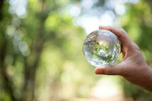 Earth crystal glass globe ball in human hand, environment day concept. Sustainable development of natural resources and the environment. Protecting the world's forest resources. photo