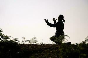 Silhouette of woman kneeling down praying for worship God at white background. Christians pray to jesus christ for calmness. In morning people got to a quiet place and prayed. copy space. photo