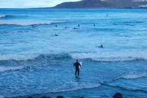 Surfers getting ready to enter the water and walking with the board along the shore. photo